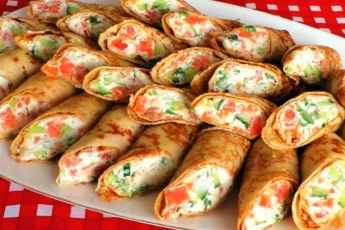 Тонкие золотистые блинчики с очень вкусной начинкой на тарелке