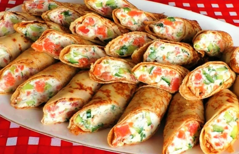 Тонкие золотистые блинчики с очень вкусной начинкой на тарелке