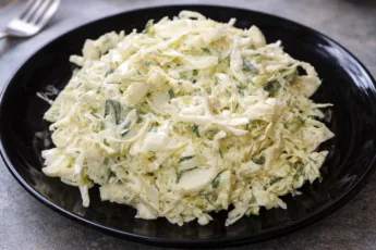 Яркий весенний салат из свежей капусты с огурцами, яйцом и зеленью в миске