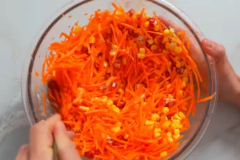 Тертая свежая морковь, зерна граната и кукуруза в глубокой тарелке