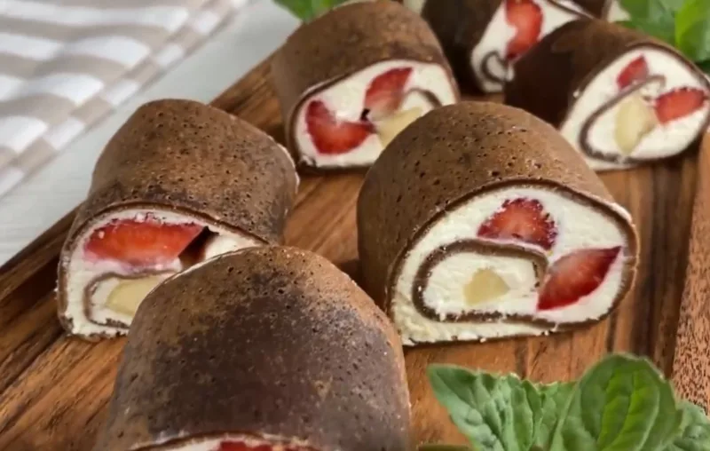 Готовый десерт: блинный рулет с нежным творожным кремом и свежей клубникой в разрезе