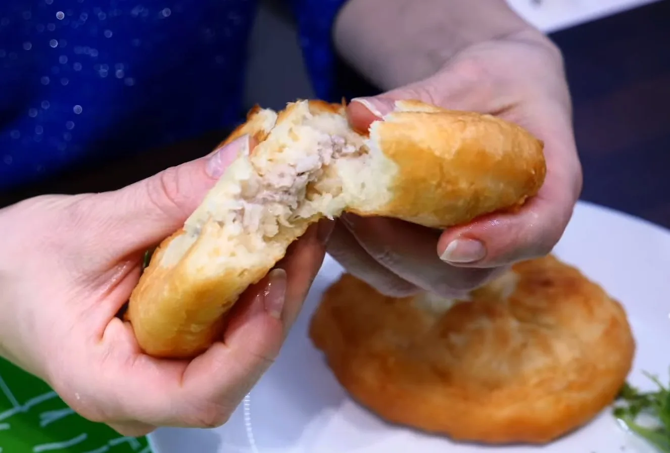 Разлом горячего домашнего беляша, виден мясной сок и пористое мягкое тесто