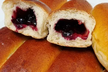 Домашние пышные пирожки с замороженной смородиной и повидлом в разрезе на противне