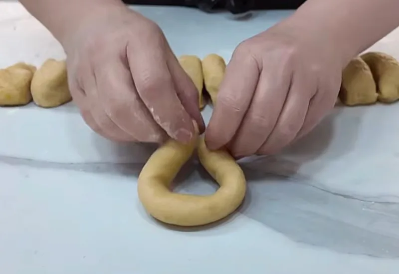 Процесс формовки лимонного печенья в виде пончиков: скрепление краев тонких колбасок теста перед выпечкой — рецепт от Виктора Ерофеева на souspark.ru