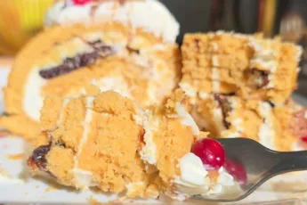 Аппетитный срез медового рулета с белым кремом, кусочками чернослива и грецкими орехами