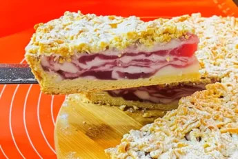 Высокий сливочный пирог в разрезе с толстым слоем нежного крема и золотистой корочкой