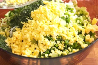 Весенний салат из пекинской капусты, свежего укропа и яиц — стадия добавления измельченного желтка перед заправкой соусом