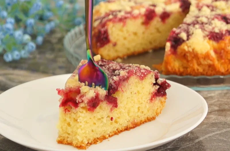 Пышный пирог с вишней, посыпанный золотистой крошкой, в разрезе виден сочный ягодный слой