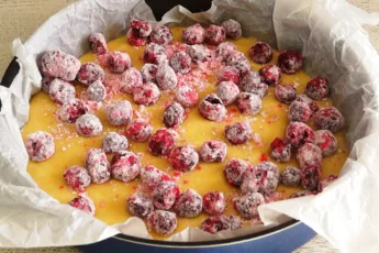 Ягоды вишни на тесте в круглой форме для выпечки, посыпанные крахмалом