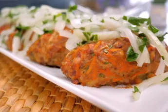 Пышные мясные котлеты на тарелке, украшенные горой тонко нарезанного маринованного лука с петрушкой