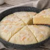 Белоснежный торт с кокосовой стружкой и белой глазурью, нарезанный на порции прямо в сковороде