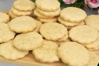 Горка круглых золотистых печений «Мария» с характерными дырочками на поверхности, лежащих на тарелке