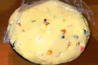 Текстура мягкого, эластичного теста с вкраплениями оранжевой апельсиновой цедры и изюма