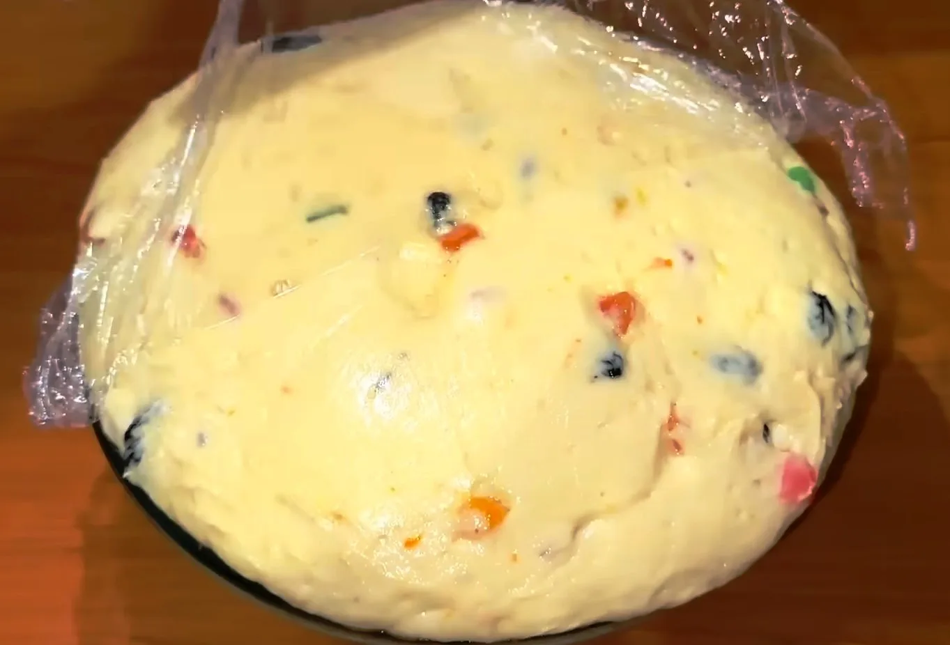 Текстура мягкого, эластичного теста с вкраплениями оранжевой апельсиновой цедры и изюма