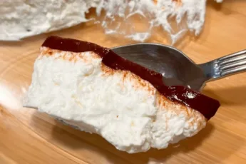 Разрез нежного белого суфле из творога под тонким слоем темной шоколадной глазури