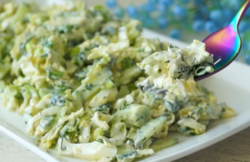 Яркий зеленый салат из пекинской капусты, огурцов и зелени, заправленный белым соусом, в прозрачной миске