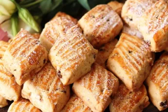 Золотистое печенье в форме ромбов с узором вилкой, посыпанное грецким орехом и сахарной пудрой