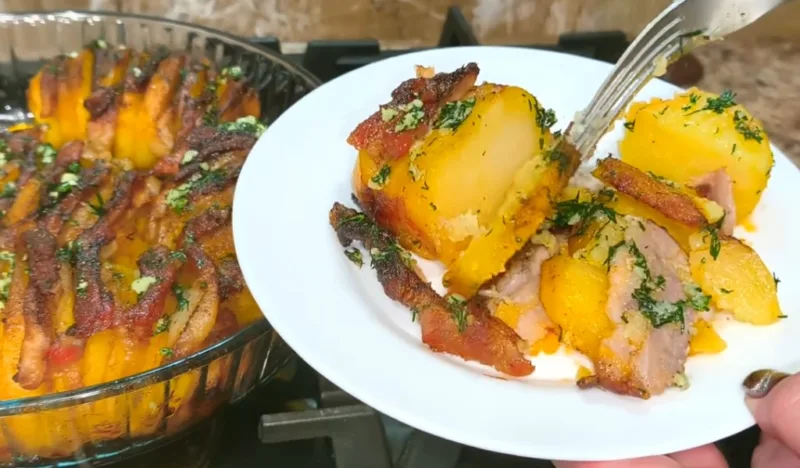 Золотистые дольки запеченного картофеля с кусочками румяной грудинки, посыпанные свежим укропом и чесноком