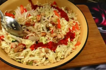 Глубокая миска с ярким салатом из жареной курицы, помидоров, огурцов и капусты, политая густым белым соусом