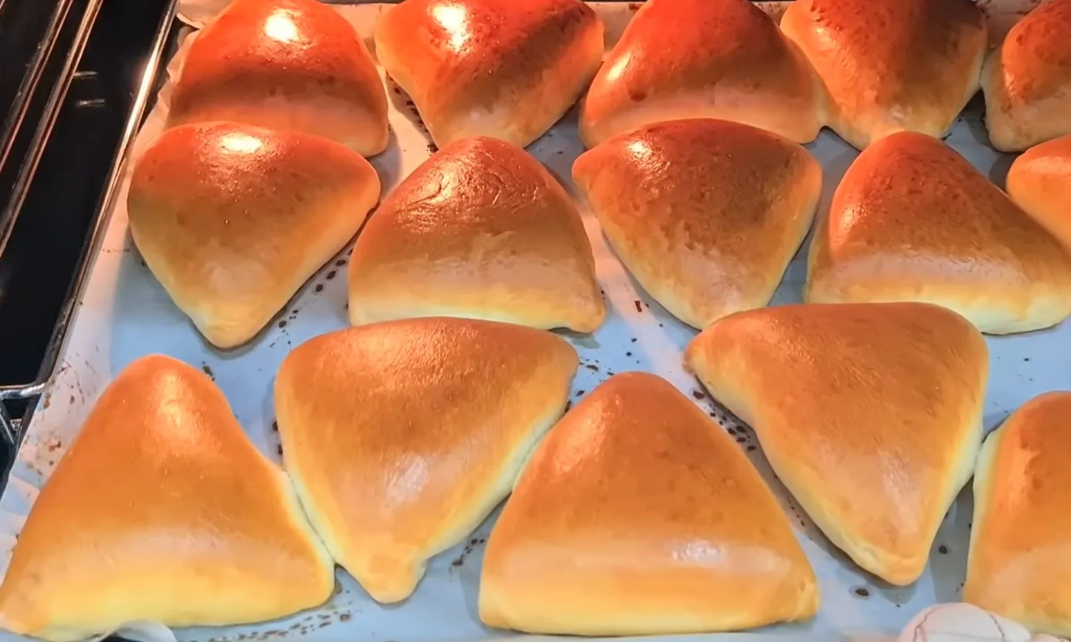 Гора румяных пышных пирожков с капустой на противне