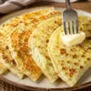 Румяные полукруглые лепешки, смазанные маслом, разложенные на деревянной доске
