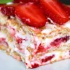 Холодный торт из слоев печенья и белого крема, густо украшенный сверху кусочками яркой клубники