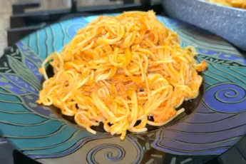 Аппетитная паста с кусочками тунца в густом розовом соусе, посыпанная специями в глубокой тарелке