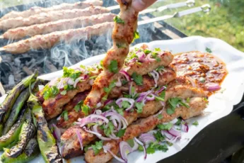 Длинные аппетитные люля-кебабы из куриного фарша с румяной корочкой, зажаренные на шампурах над углями