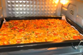 Большая румяная домашняя пицца с кусочками ветчины, половинками черри и расплавленным сыром