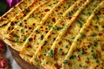 Румяные полукруглые лепешки с зеленью, смазанные маслом