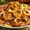 Горка румяных поджаристых кусочков куриной печени в кляре, украшенных тонкими кольцами лука