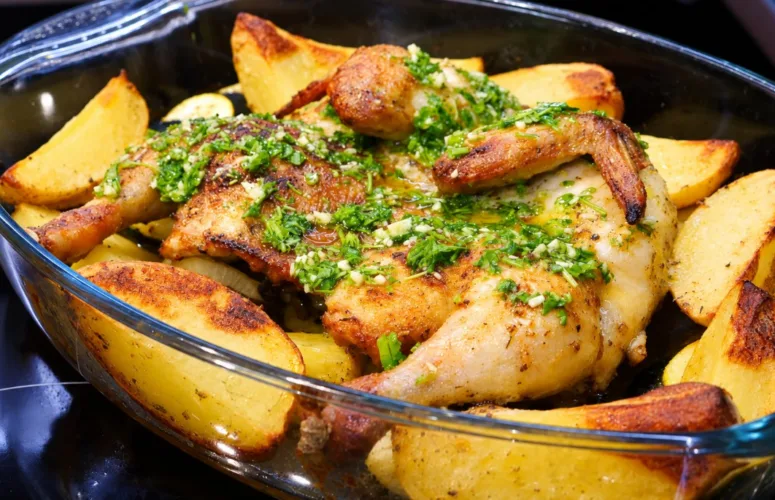Большой глубокий противень со светлой румяной курицей, разложенной плоской «книжкой», вокруг лежат золотистые дольки картофеля и зеленые кружки кабачков