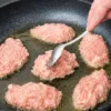 Румяные мясные оладьи с фаршем на кефире в сковороде, готовые к подаче с гарниром