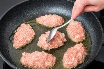 Румяные мясные оладьи с фаршем на кефире в сковороде, готовые к подаче с гарниром