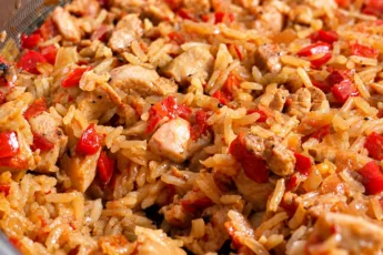 Ароматный рис с кусочками курицы, сладким перцем и томатами в широкой сковороде, готовый к подаче на семейный ужин