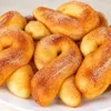 Золотистые яблочные крендельки на тарелке, посыпанные сахаром с корицей