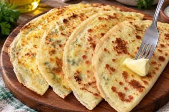 Горячая лепешка с творожной начинкой, золотистая хрустящая корочка, видна сочная творожно-чесночная масса внутри, на деревянной доске