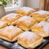 Порционный мини-«Наполеон» с тремя хрустящими слоями и белым кремом между ними, посыпан сахарной пудрой сверху