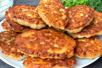 Пышная стопка румяных жареных ленивых беляшей с мясной начинкой на белой тарелке.