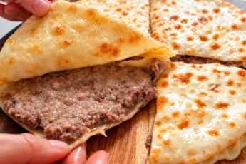 Румяный закрытый мясной пирог с сочной начинкой из фарша и лука, обжаренный на сковороде